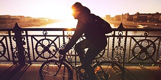 Mobilität viktorkeri © Unsplash Mann fährt auf seinem Fahrrad auf einer Brücke im Sonnenuntergang