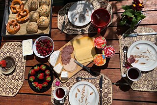 Gedeckter Frühstückstisch mit Kaffee, Brötchen, Brezeln und Erdbeeren