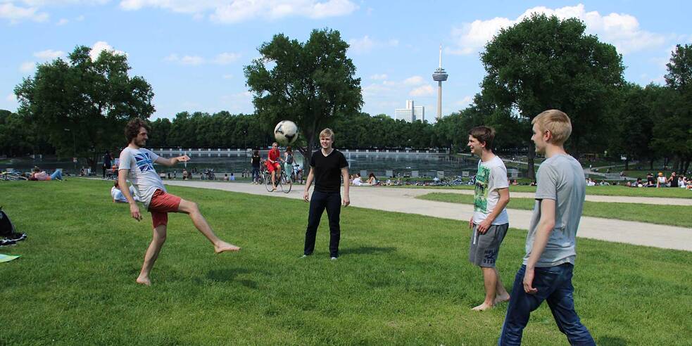 David , Kai, Markus und Johannes spielen Fußball im Park 