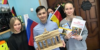 Schüler und Schülerinnen mit Flaggen, Deutschbüchern und dem Brandenburger Tor
