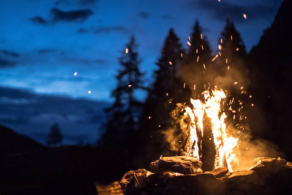 Lagerfeuer im Dunkeln mit Bäumen im Hintergrund