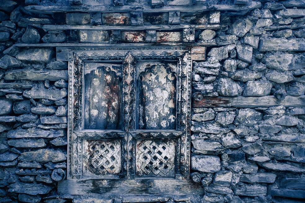 Holzfenster in einem aus vielen verschiedenen blauen Steinen zusammengesetzten Haus