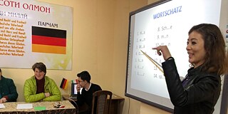 Lehrerin steht vor der Klasse und unterrichtet deutsche Grammatik
