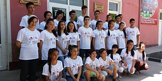 Schülerinnen und Schüler in PASCH-T-Shirts stehen vor der Schule