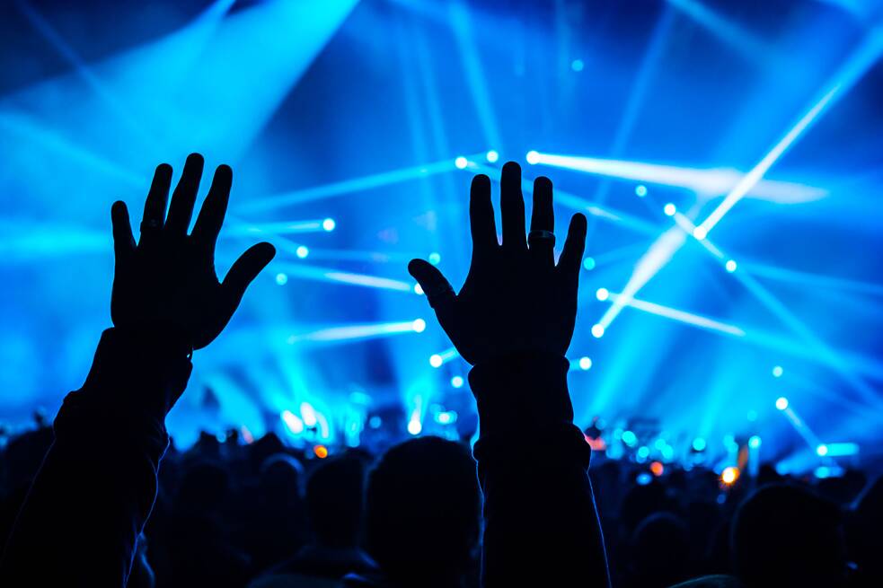 Zwei Hände werden bei einem Konzert in die Luft gehalten