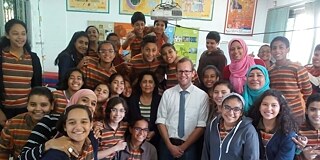 Gruppenfoto von Schülerinnen und Schülern in einem Klassenraum mit Lehrkraft in der Mitte