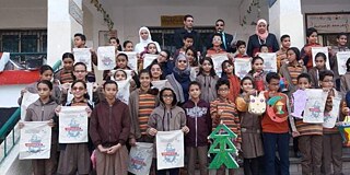 Gruppenfoto der Schülerinnen und Schüler vorm Haupteingang mit Tannenbaum aus Holz