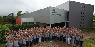 Gruppenfoto vor dem Kindergartengebäude, alle halten die Hände in die Luft