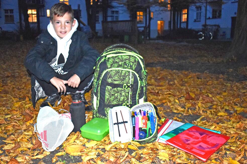 Leo sitzt neben seiner ausgepackten Schultasche