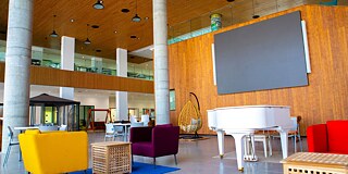 Bunte Sofas, ein weißer Flügel und ein großer Bildschirm an der Wand im Gebäude