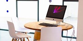 Hochtisch mit Stühlen und einem aufgeklappten Laptop