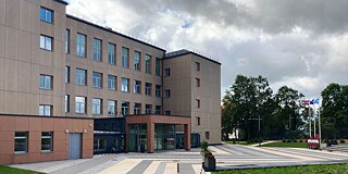 Graues Schulgebäude mit Rasenfläche