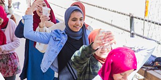 Schülerinnen laufen hintereinander her, lachen und tragen Wassergläser