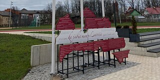 Rotes Schild aus Holz mit Schrift auf dem Schulhof