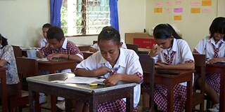 Schülerinnen in Schuluniformen sitzen im Unterricht und schreiben