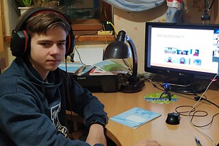 Junge mit Headset vor seinem Rechner