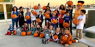 Gruppenbild am Hafen, Kinder in Halloween-Verkleidung und mit geschnitzten Kürbissen