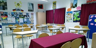 Einblick in einen Klassenraum mit hochgestellten Stühlen und Postern zum Thema Deutschland an der Wand