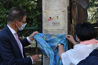 Die PASCH-Plakette an der Freien Waldorfschule Tbilissi wird von zwei Personen enthüllt.