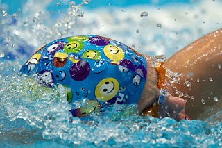 Mann mit Schwimmhaube krault im Wasser