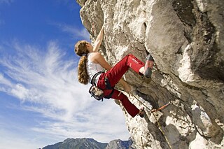 Mädchen klettert an einem Felsen hoch