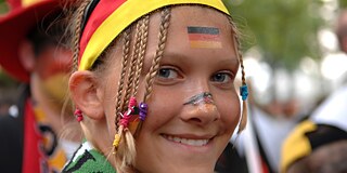 BKD-Kalender 2018 © picture-alliance / Fotograf: Sven Simon Mädchen, geschminkt mit Deutschlandfahne auf der Wange