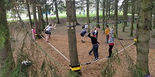 Schüler klettern gesichert im Wald