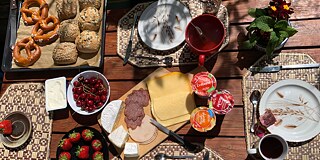 Gedeckter Frühstückstisch mit Kaffee, Brötchen, Brezeln und Erdbeeren