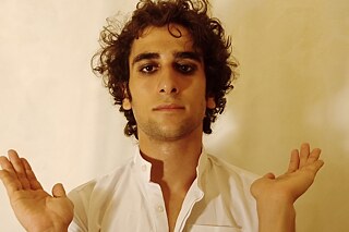 Achmed Elalfy Selbstporträt © Goethe-Institut Tunis Mann in weißem Oberteil hält die Hände mit den Handflächen nach oben und schaut in die Kamera