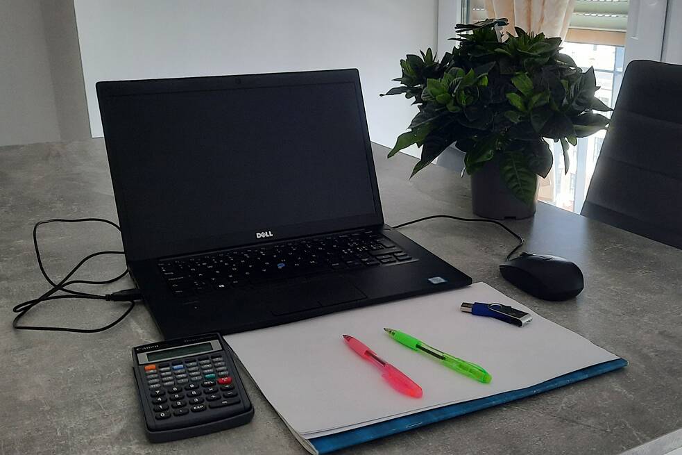 Laptop und aufgeklapptes Notizbuch auf einem Tisch