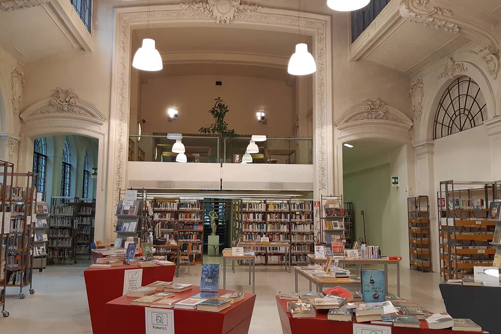 Innenansicht der Stadtbibliothek mit stuckverzierten Wänden und Türen, roten Tischen und Bücherregalen