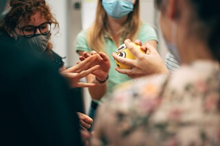 Mehrere Personen stehen zusammen, eine Person hält einen kleinen Ball in der Hand