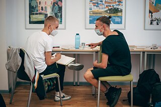 Zwei Männer sitzen an einem Tisch und unterhalten sich