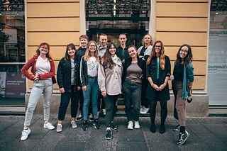 kulturweit-Freiwillige stehen zusammen vor einem Gebäude und lächeln in die Kamera