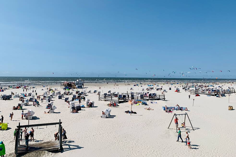 Strand mit vielen Menschen und Strandkörben, im Hintergrund das Meer