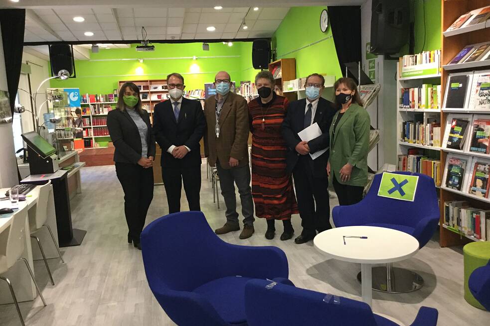 Eine Gruppe von Menschen steht in einem Raum mit vielen Bücherregalen zusammen