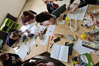 Schüler und Schülerinnen beim Bemalen von Stofftaschen, von oben fotografiert