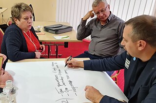 Workshop © Goethe-Institut Drei Personen sitzen an einem Tisch vor einem Blatt Papier und diskutieren