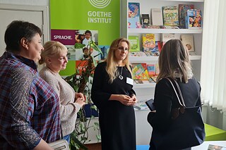 Vier Schulleiterinnen stehen vor einem Banner des Goethe-Instituts und unterhalten sich