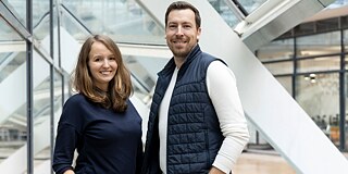Lichter der Welt © Daniel Herrmann Ein Mann und eine Frau stehen nebeneinander vor einer Fensterfront und lächeln