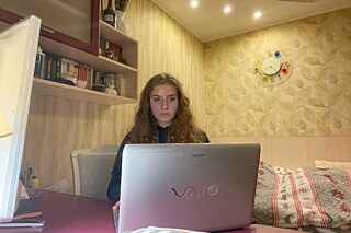 Teilnehmerin mit Laptop auf ihrem Bett in ihrem Zimmer