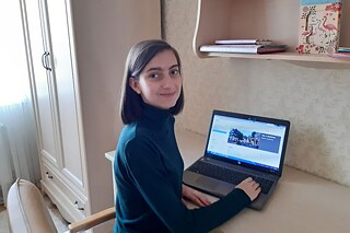 Teilnehmerin vor ihrem Laptop in ihrem Zimmer