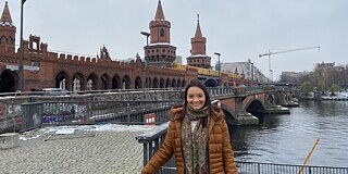Larissa © privat Larissa in einer braunen Jacke vor einer Brücke aus rotbraunen Steinen