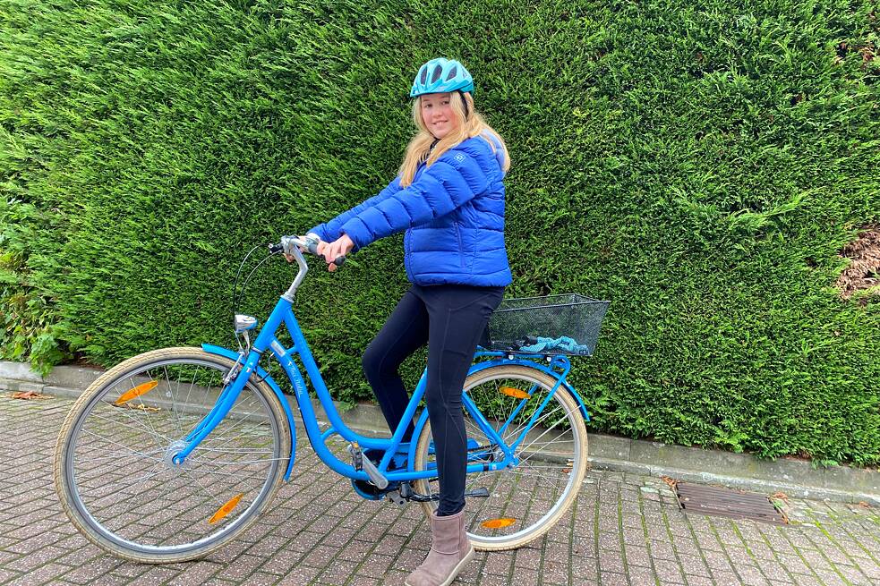 Lara-Sophie (11 Jahre): Mit einem blauen Fahrrad vor einer Hecke