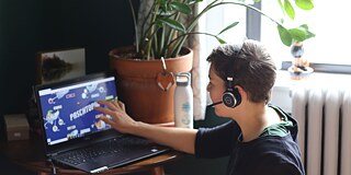 Frau mit Headset vor einem Laptop, auf dem PASCHTOPIA steht