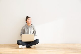Deine Zukunft in MINT! © Goethe-Institut Korea/Getty Images Eine junge Frau sitzt im Schneidersitz am Boden an die Wand gelehnt. Sie hat einen Laptop auf Schoß und schaut in die Luft.