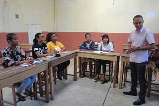 Mehrere Schülerinnen und Schüler mit ihrer Lehrkraft in einem Klassenraum