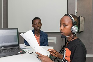 Ein Jugendlicher mit Kopfhörern hält ein Skript in der Hand