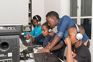 Mehrere Jugendliche arbeiten an Laptops mit Kopfhörern auf