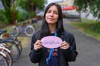 Eine Jugendliche hält eine Karte mit ihrem deutsches Lieblingswort „Schildkröte“ vor sich.